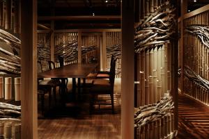 a dining room with a table and chairs and a wall of wine racks at 間人温泉 炭平 in Kyotango