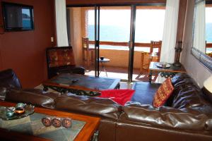 a living room with a leather couch and a balcony at Pinacate Rocky Point By Castaways in Puerto Peñasco