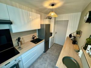 eine Küche mit weißen Schränken und einer Holzarbeitsplatte in der Unterkunft Appartement 4 personnes idéal Disney et Paris in Torcy + 16 Fotos