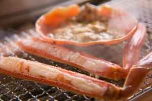 three slices of bacon cooking on a grill at 間人温泉 炭平 in Kyotango