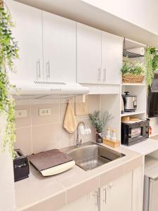 a kitchen with white cabinets and a sink at Apaisante Tropical Lodge in Tagaytay