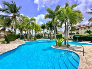 a large swimming pool with palm trees in a resort at Villa 122 Sugar Hill Estate, pools, tennis, gym, 5 mins to beach in Saint James