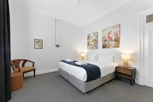 una camera da letto bianca con un letto e una sedia di Dunkley House - Large CBD Heritage Home, Sleeps 10 a Bathurst