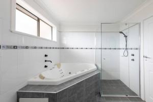 Un baño blanco con bañera y ducha. en Dreamtime Beach Retreat - 4 Bedroom with Ocean View, en Forster 23 fotos más