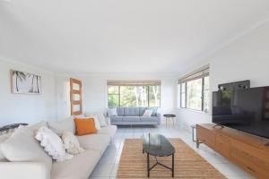 Una sala de estar con un sofá blanco y un televisor. en Dreamtime Beach Retreat - 4 Bedroom with Ocean View, en Forster