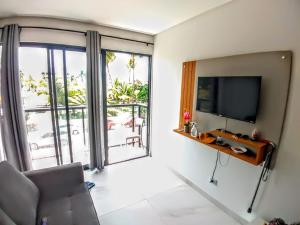 a living room with a flat screen tv and a couch at Flat 104 - Na Rua das Piscinas Naturais no Centro de Porto de Galinhas in Porto De Galinhas