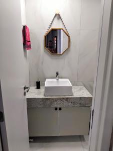 a bathroom with a white sink and a mirror at Flat 104 - Na Rua das Piscinas Naturais no Centro de Porto de Galinhas in Porto De Galinhas