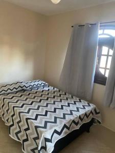 Schlafzimmer mit einem schwarzen und weißen Bett und einem Fenster in der Unterkunft casa de Vilatur in Saquarema