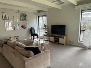 Una sala de estar con un sofá y un televisor de pantalla plana. en Close to the Shops Beach, Perfect for 2 Families, en Inverloch
