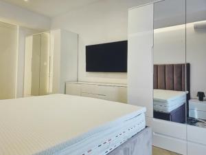 Un dormitorio blanco con una cama y un televisor. en Lazuly 2 BDR Luxury, en Varna