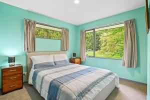 a blue bedroom with a bed and two windows at Family Hideaway in Hanmer Springs