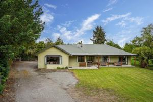 a small yellow house with a grass yard at Family Hideaway in Hanmer Springs