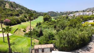 a view of a golf course with a house at Las Jacarandas Penthouse with Stunning Views & Private Rooftop in Benahavís
