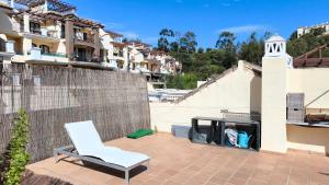 a white chair sitting on a patio with a fire place at Las Jacarandas Penthouse with Stunning Views & Private Rooftop in Benahavís