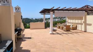 a patio with chairs and a pergola on a building at Las Jacarandas Penthouse with Stunning Views & Private Rooftop in Benahavís