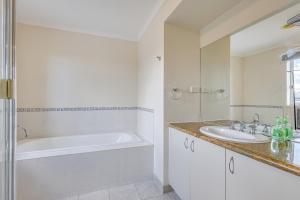 a white bathroom with a tub and a sink at StayAU Family Home Comfort in Caroline Springs in Caroline Springs +62 photos