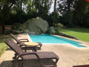 a pool with chairs and a table next to a rock at El Refugio de los Ángeles in San Antonio del Tequendama