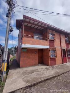 Un edificio de ladrillo rojo con un balcón. en Hostal casa Claudia in Jardin Antioquia, en Jardín