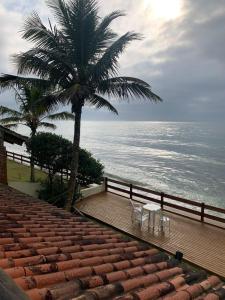 un palmier et des chaises sur une promenade près de l'océan dans l'établissement Casa BEIRA MAR Praia do Grant em Barra Velha-SC, à Barra Velha