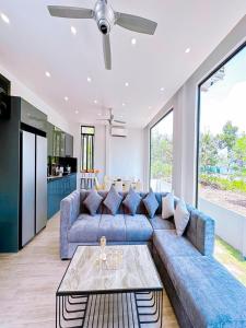 un salon avec un canapé bleu et une table dans l'établissement Chuỗi Villa Tuần Châu 8 Ngủ - Bể bơi riêng - sân vườn - BBQ, à Hạ Long