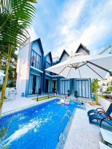 une maison avec une piscine entourée d'un parasol dans l'établissement Chuỗi Villa Tuần Châu 8 Ngủ - Bể bơi riêng - sân vườn - BBQ, à Hạ Long