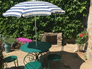 une table avec un parasol bleu et blanc et deux chaises dans l'établissement Gîte authentique avec wifi, cheminée à Véranne - FR-1-496-255, à Véranne 5 autres photos