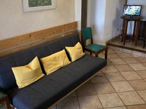 - un canapé bleu avec des oreillers jaunes dans l'établissement Gîte authentique avec wifi, cheminée à Véranne - FR-1-496-255, à Véranne