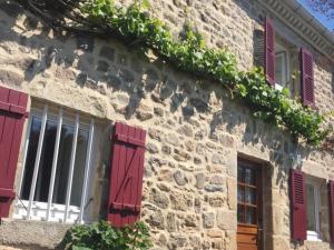 un bâtiment en pierre avec des fenêtres à volets rouges et du lierre dans l'établissement Gîte authentique avec wifi, cheminée à Véranne - FR-1-496-255, à Véranne