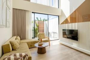 Una sala de estar con un sofá y un televisor. en Oasis Villa 8 by Betterplace, en Canggu