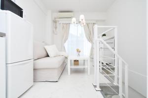 a white living room with a white couch and a ladder at Bijou Suites Lohas in Osaka