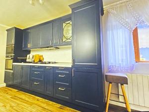 a kitchen with black cabinets and a stool in it at Luxury villa with sea view 1min to beach in Varna City