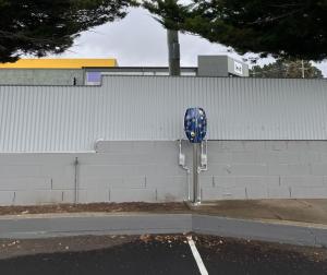 a blue parking meter in a parking lot next to a wall at Cooma Motor Lodge Motel in Cooma +1 photo