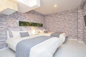 two beds in a room with a brick wall at Bijou Suites Lohas in Osaka