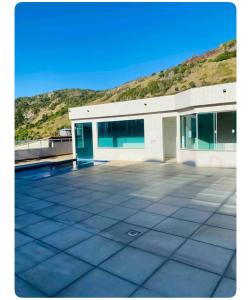 un grand bâtiment blanc avec une montagne en arrière-plan dans l'établissement Apartamento canto da Prainha, à Arraial do Cabo