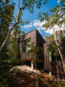 a wooden house in the woods with trees at Black Spruce - Yellow Door in Whitehorse