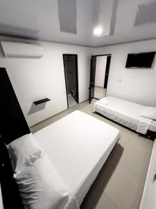 two beds in a room with white walls at Hotel bazurto plaza in Cartagena de Indias