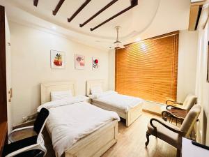 two beds in a room with a window at Holidazzle Lodge Islamabad in Islamabad