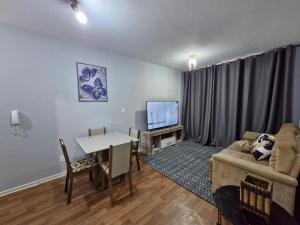 a living room with a couch and a table and a tv at Apto no Centro de São Leopoldo in São Leopoldo