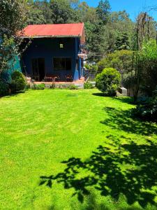 una casa con techo rojo y patio verde en Alojamiento tipo Cabaña, rodeado de Bosque, en Ciudad de México
