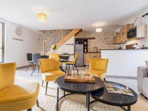 a living room with a table and yellow chairs at Ancien corps de ferme rénové avec jardin, terrasse et recharge EV, à 24 km de Nantes - FR-1-306-1282 in Saint-Colomban +9 photos