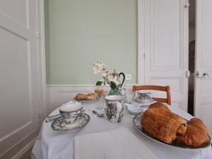a table with croissants and cups and a plate of bread at Chambre chaleureuse "Toscane" avec lit 160cm, salle d'eau privative et petit-déjeuner inclus. - FR-1-591-600 in Châteauroux +11 photos