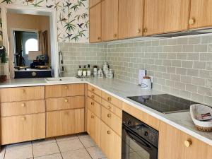 a kitchen with wooden cabinets and a sink and a stove at Maison Trianon 1928 in Quiévrechain