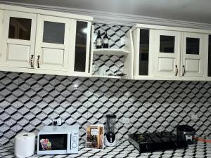 een keuken met witte kasten en een aanrecht met een magnetron bij Costal Vibe Escapes in Monrovia