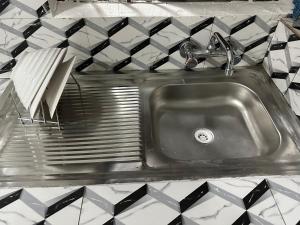 een roestvrijstalen wastafel in een keuken met zwarte en witte tegels bij Costal Vibe Escapes in Monrovia