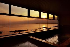 a room with a view of the ocean through windows at Hayama Umino Hotel in Hayama