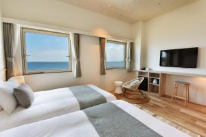 a bedroom with a bed with a tv and two windows at Hayama Umino Hotel in Hayama