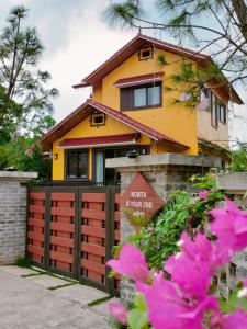 a yellow house with a red gate and pink flowers at Nobita Villa Venuestay in Hanoi
