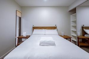 una camera da letto con un grande letto bianco e scaffali di Modern apt in heart of the city a Canberra