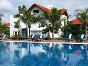 a pool in front of a resort with chairs and palm trees at EG Paradise Angkor Villa Hotel in Siem Reap