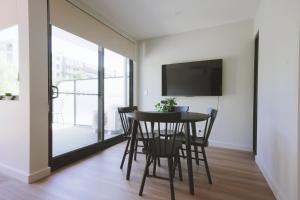 una sala da pranzo con tavolo, sedie e TV di Modern apt in heart of the city a Canberra